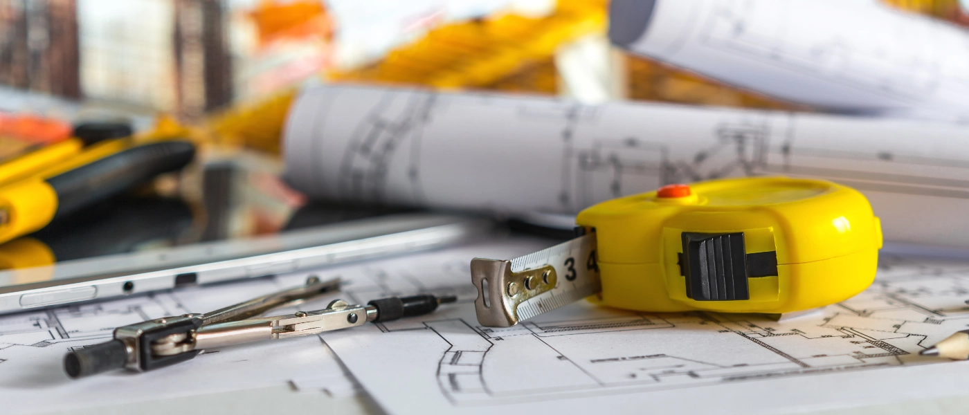 Papers with blueprints printed on them, next to measuring tools